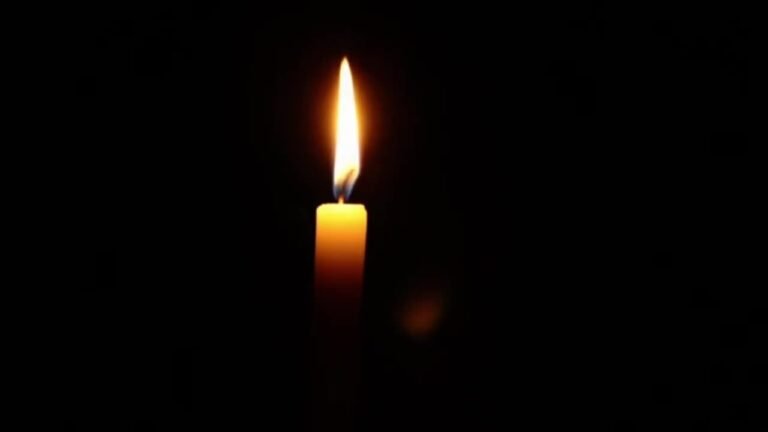 A single lit candle with a bright flame against a dark background.