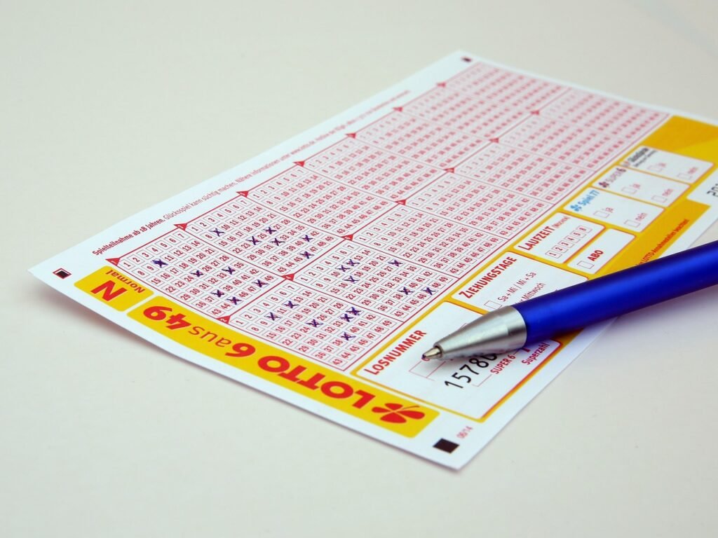 Lotto ticket with numbered grids and a blue pen resting on it, displaying various selections and a barcode.