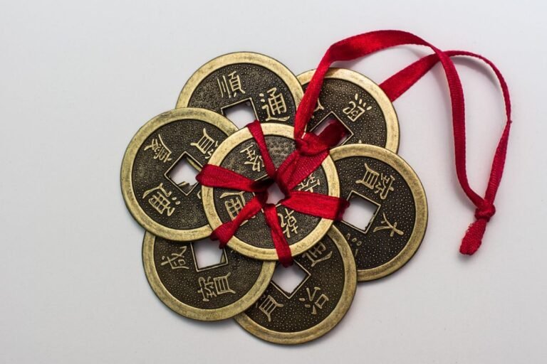 A collection of Chinese coins tied together with a red ribbon, featuring traditional inscriptions on their surfaces.